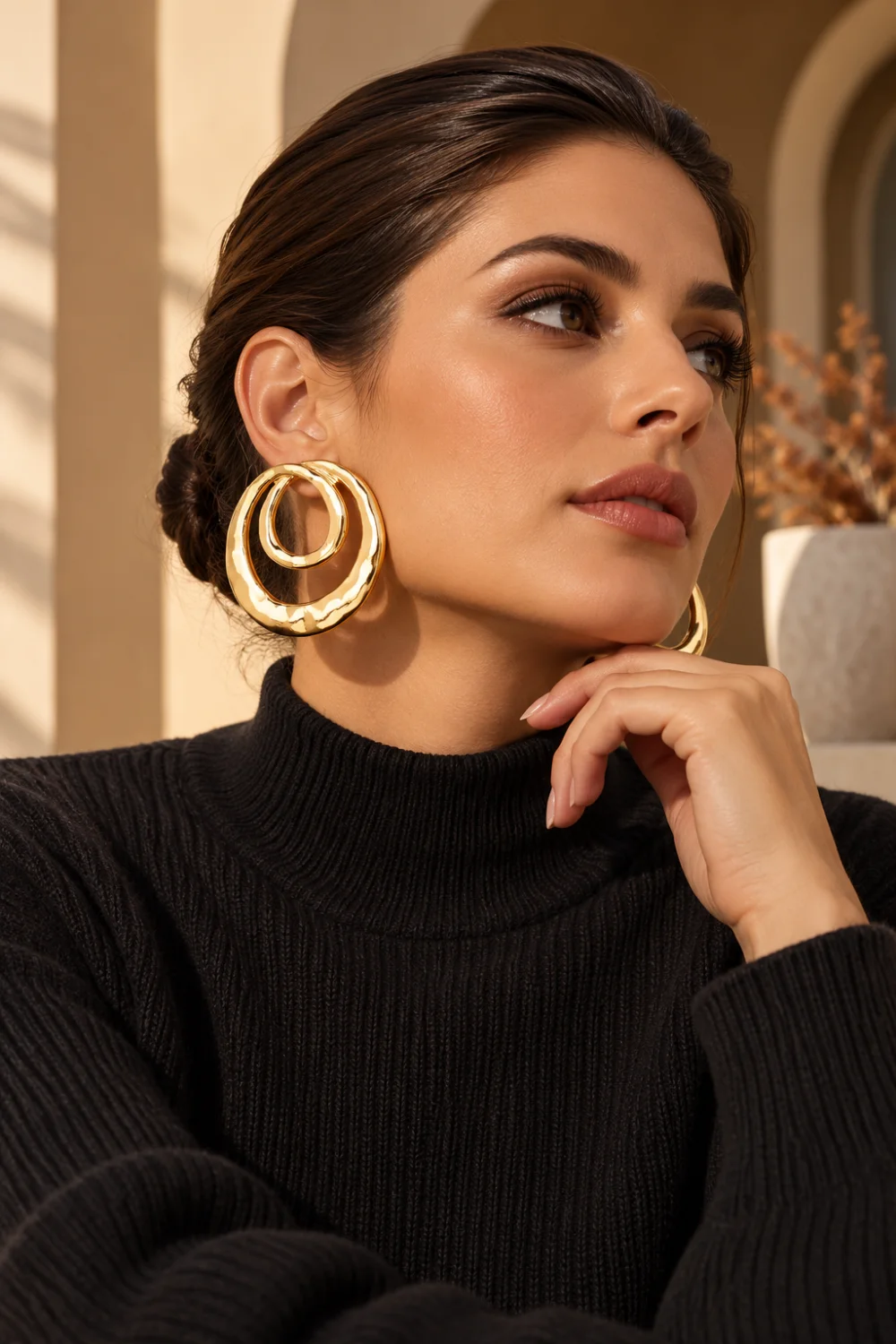 Sculptural oversized gold statement earrings with a black sweater